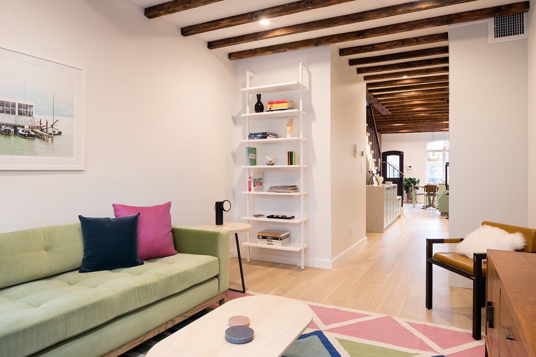 Greenpoint townhouse living room looking toward the front windows, with a green sofa, open shelving and timber beams
