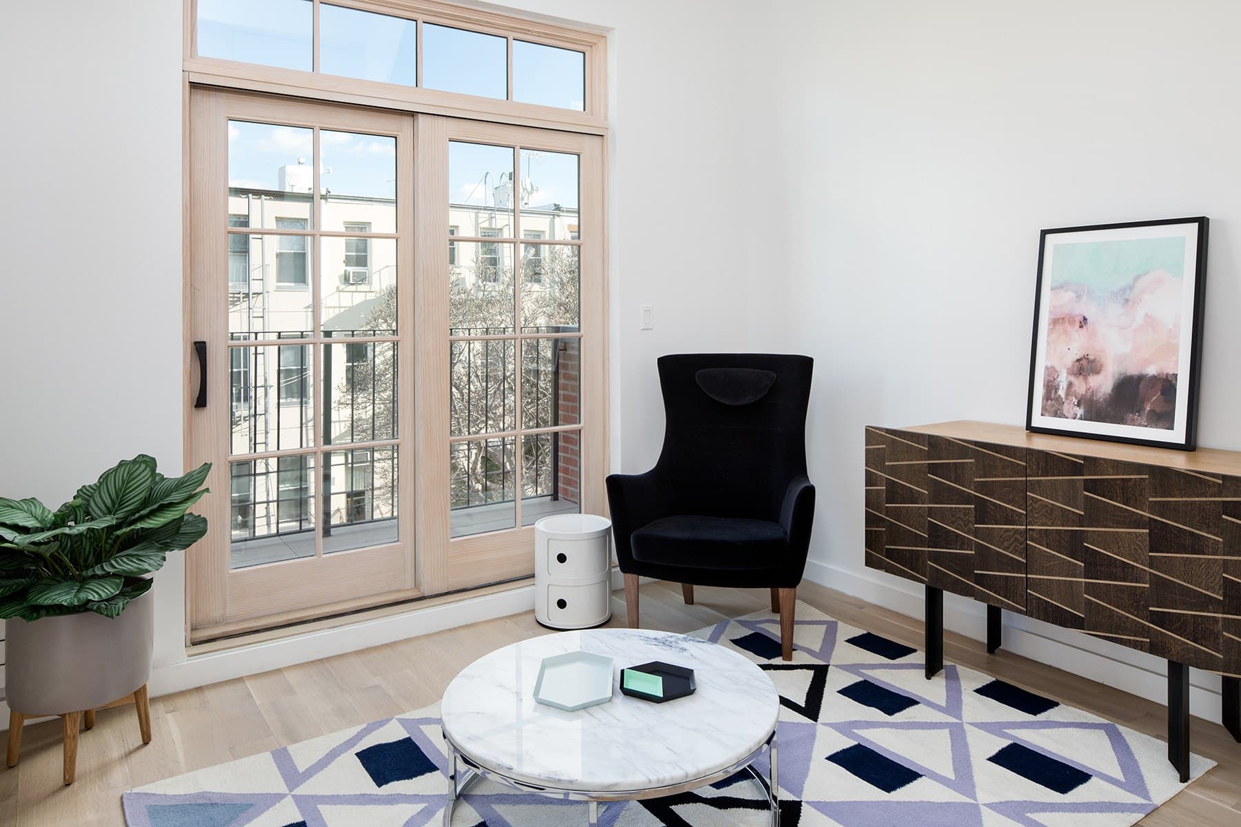 Back room with a marble table, an armchair and French doors