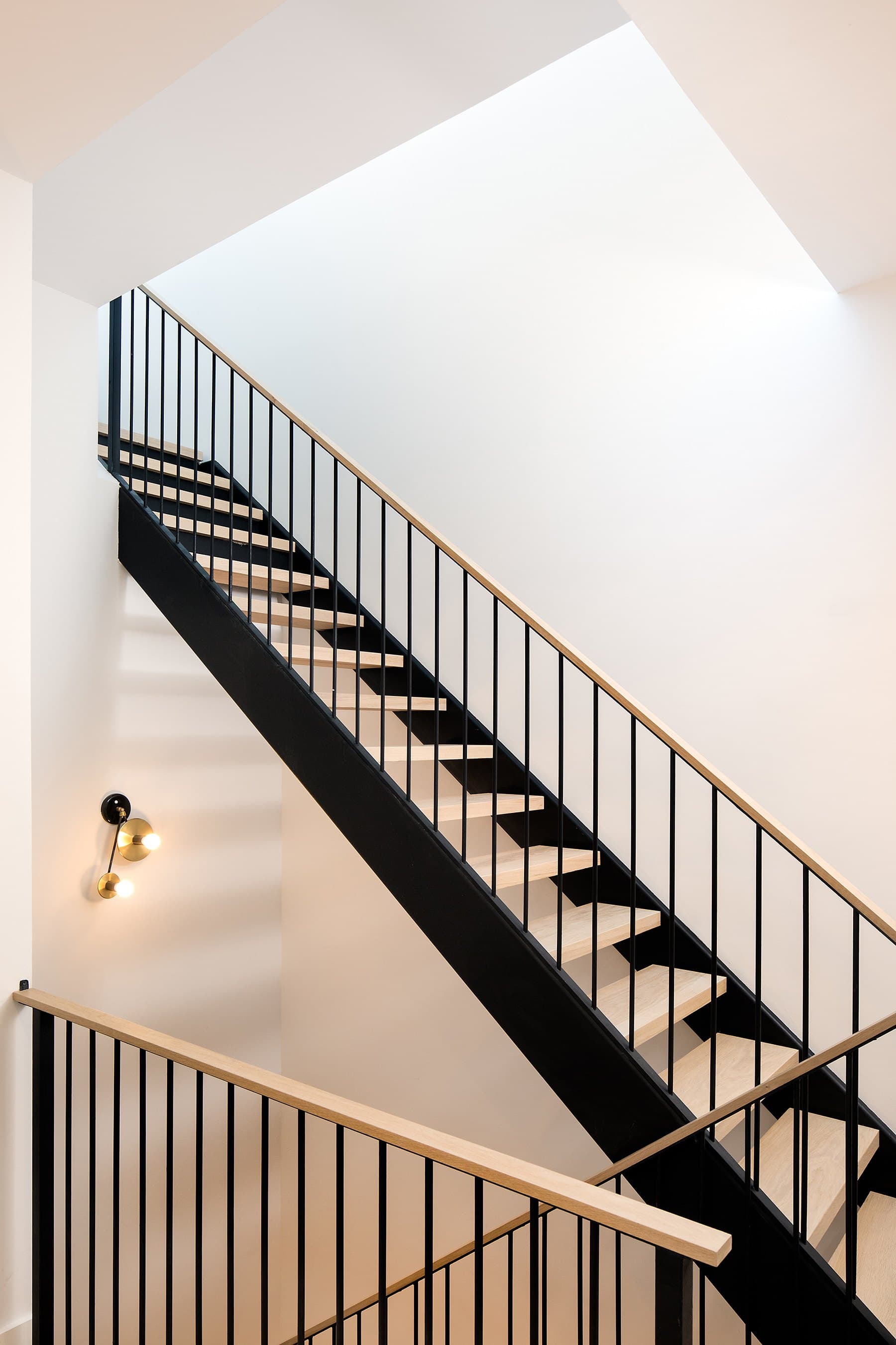 Black steel stair rising toward a skylight