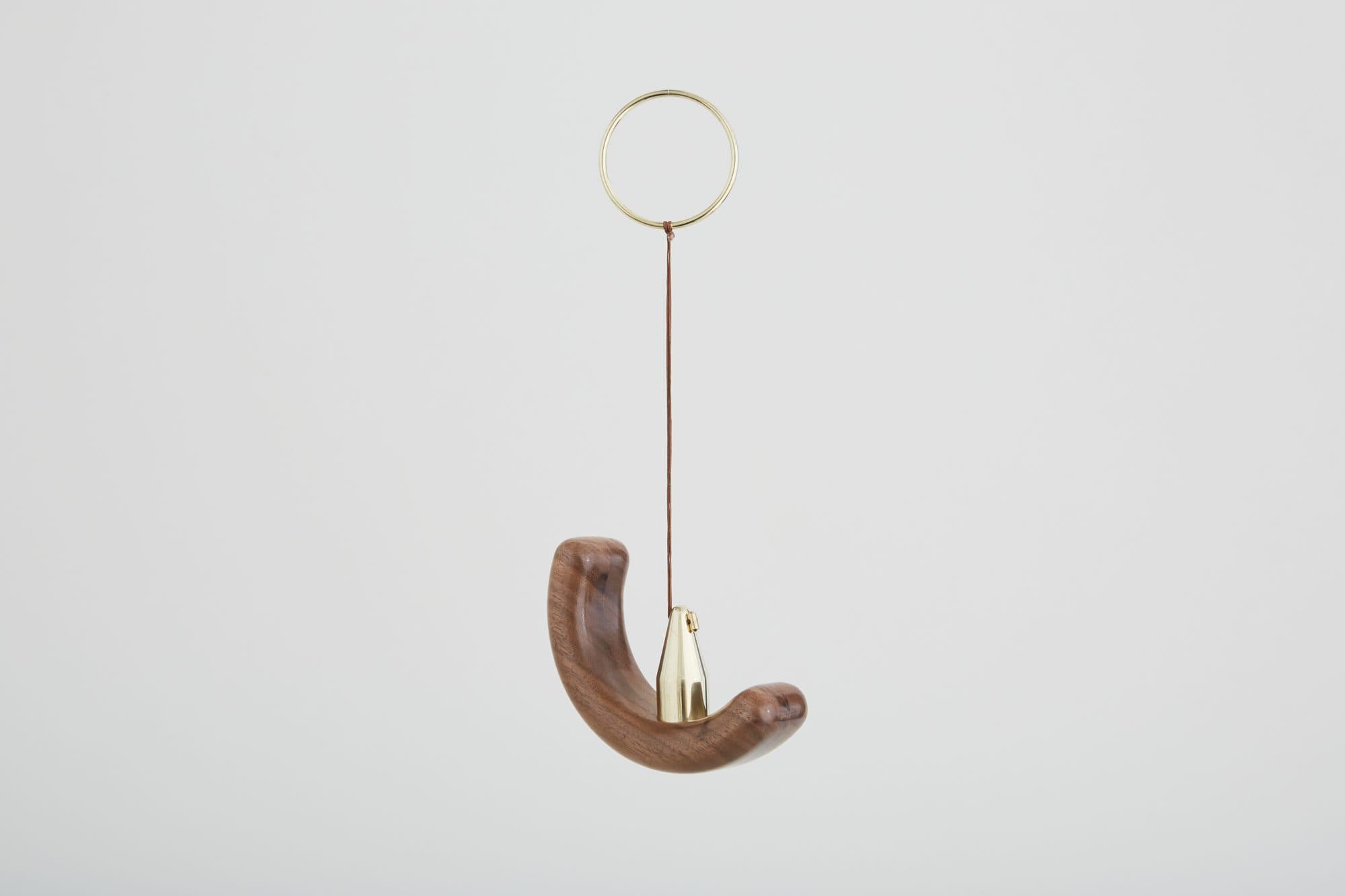 Carved walnut crescent on a brass hoop by Fernweh Woodworking