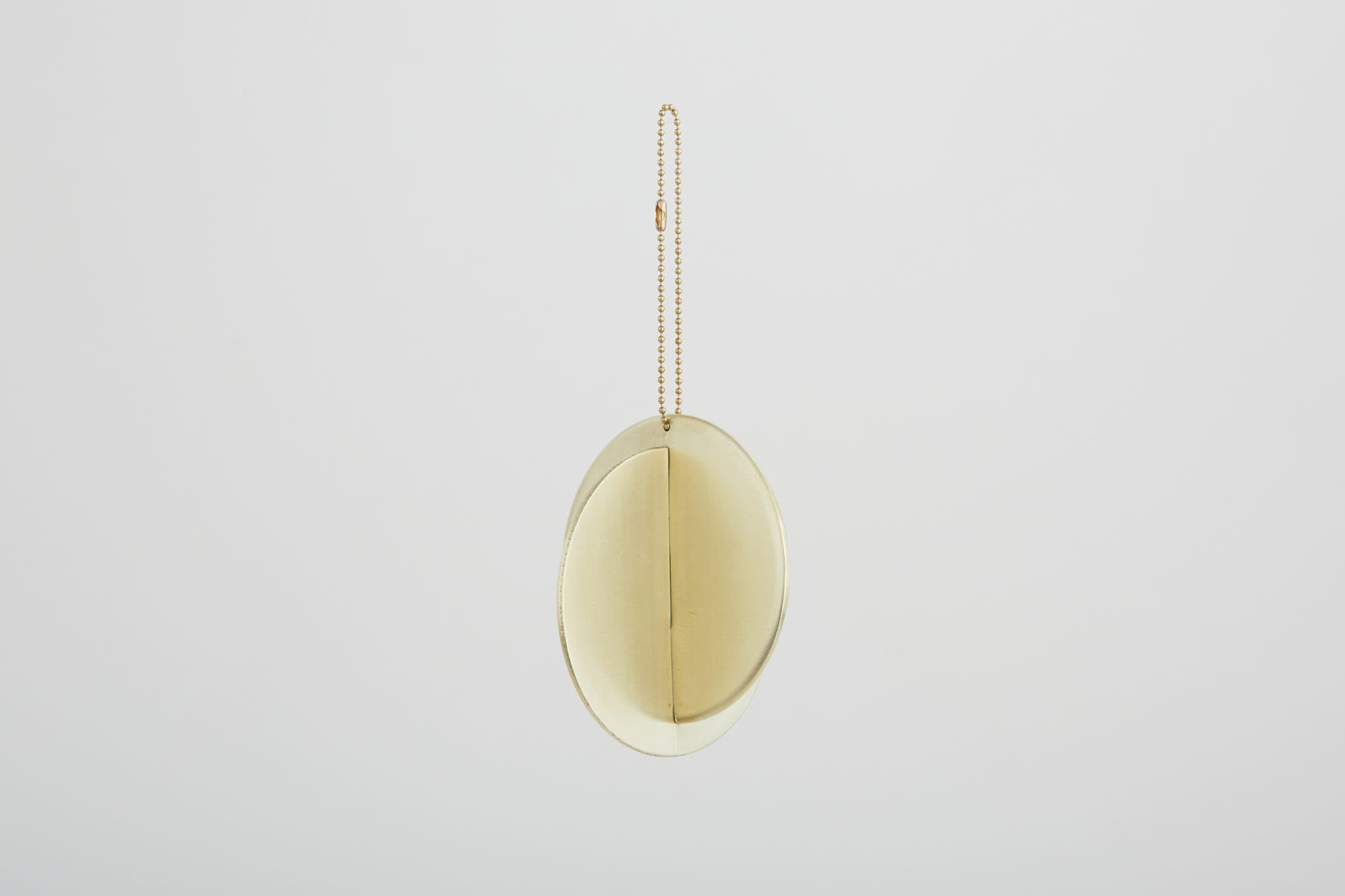 Pale oval ornament on a brass ring by Kiel Mead