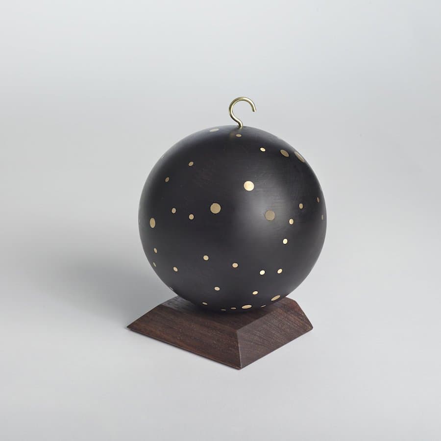 Black sphere with gold dots on a walnut stand by Asher Israelow