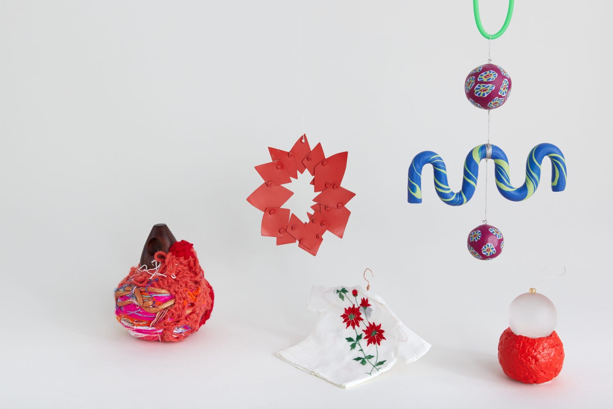 Holiday ornaments including a red paper star by Noble Goods, a blue glass squiggle by Another Human and an embroidered shirt by Bode