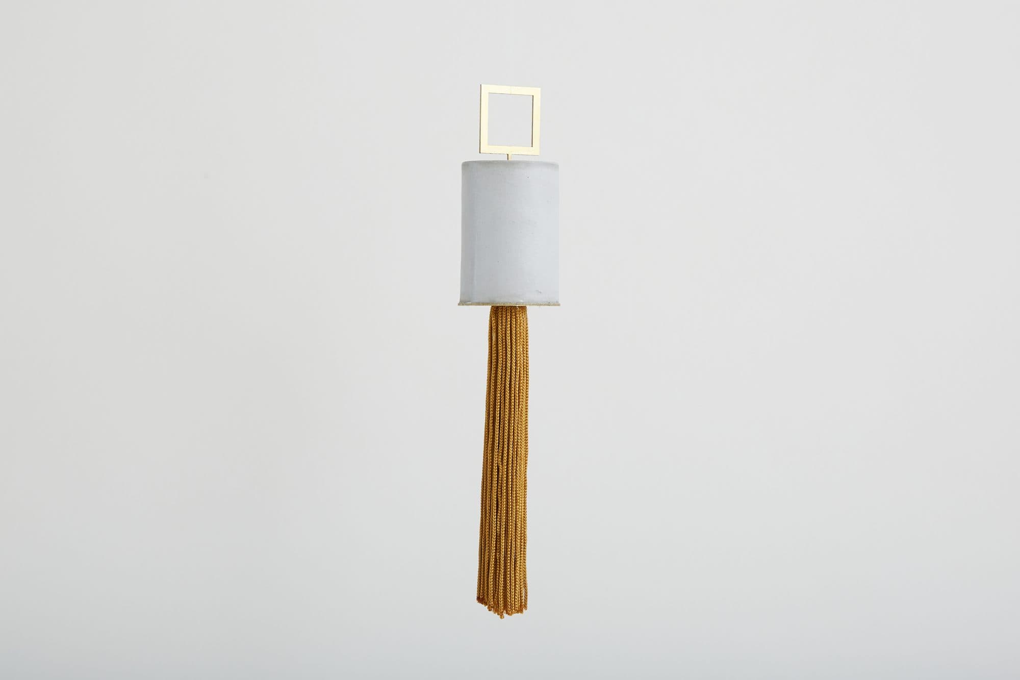 White and brass tassel ornament by Slash Objects