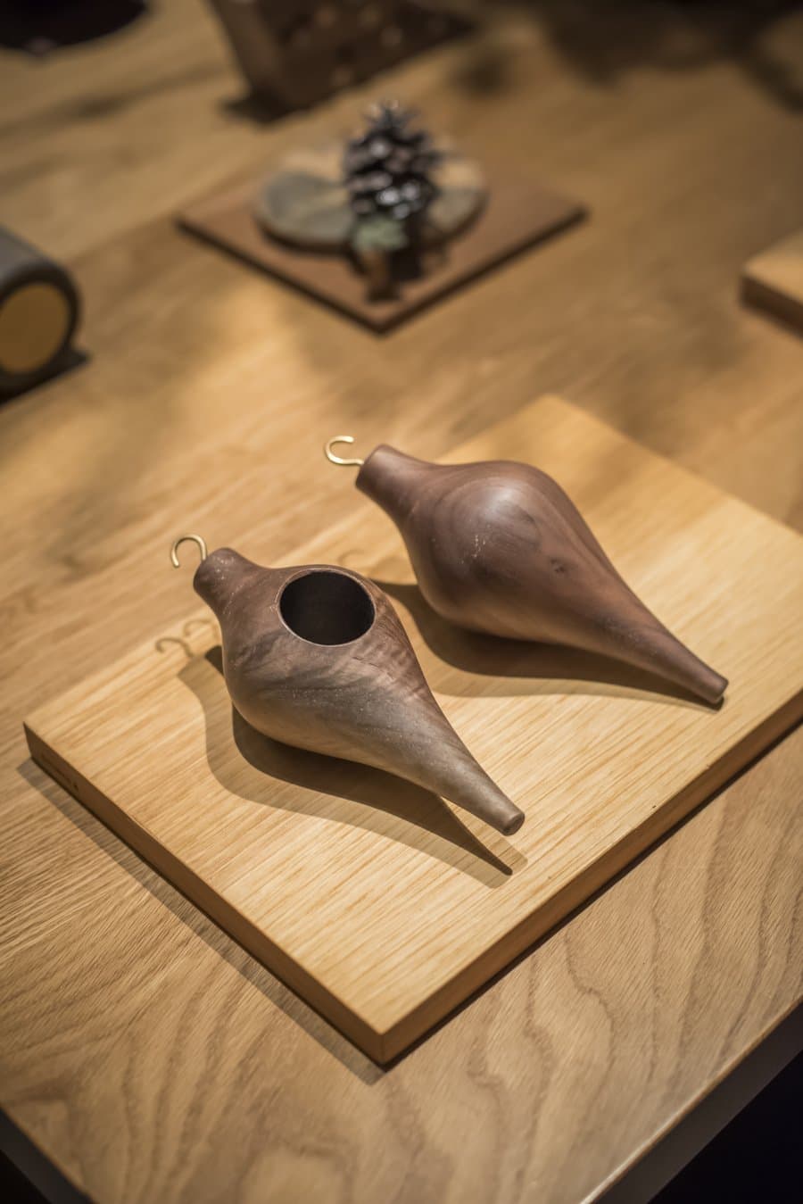 Pair of carved walnut ornaments by SHIMNA on a wood plinth