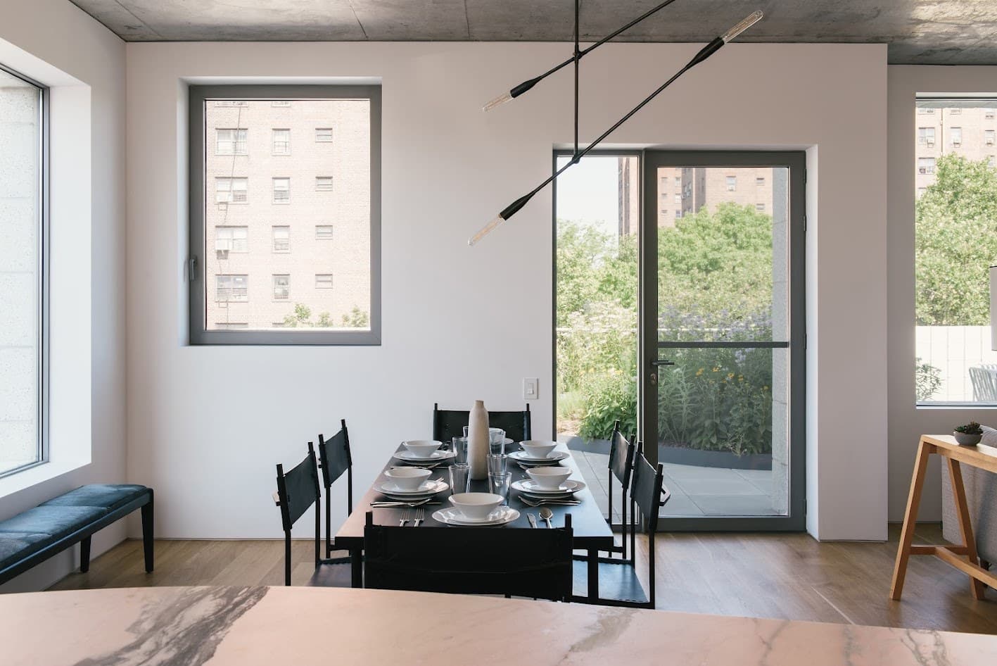 Dining table with black leather chairs, a sculptural pendant and the oak kitchen island at 450 Warren