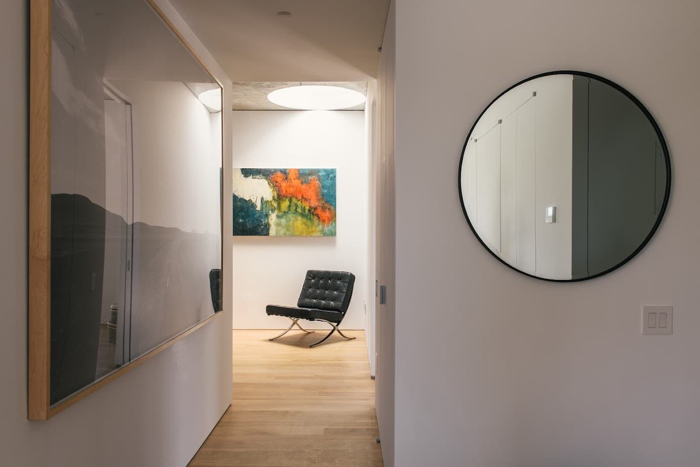 Hallway with a round mirror and a view to a leather lounge chair