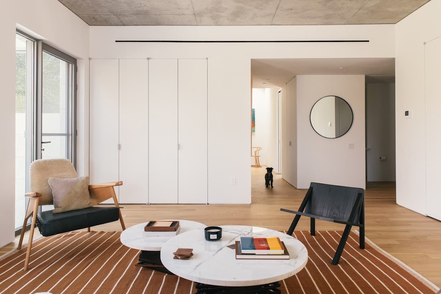 450 Warren penthouse living room with a grey sofa, black and tan lounge chairs and marble coffee tables on a striped rug