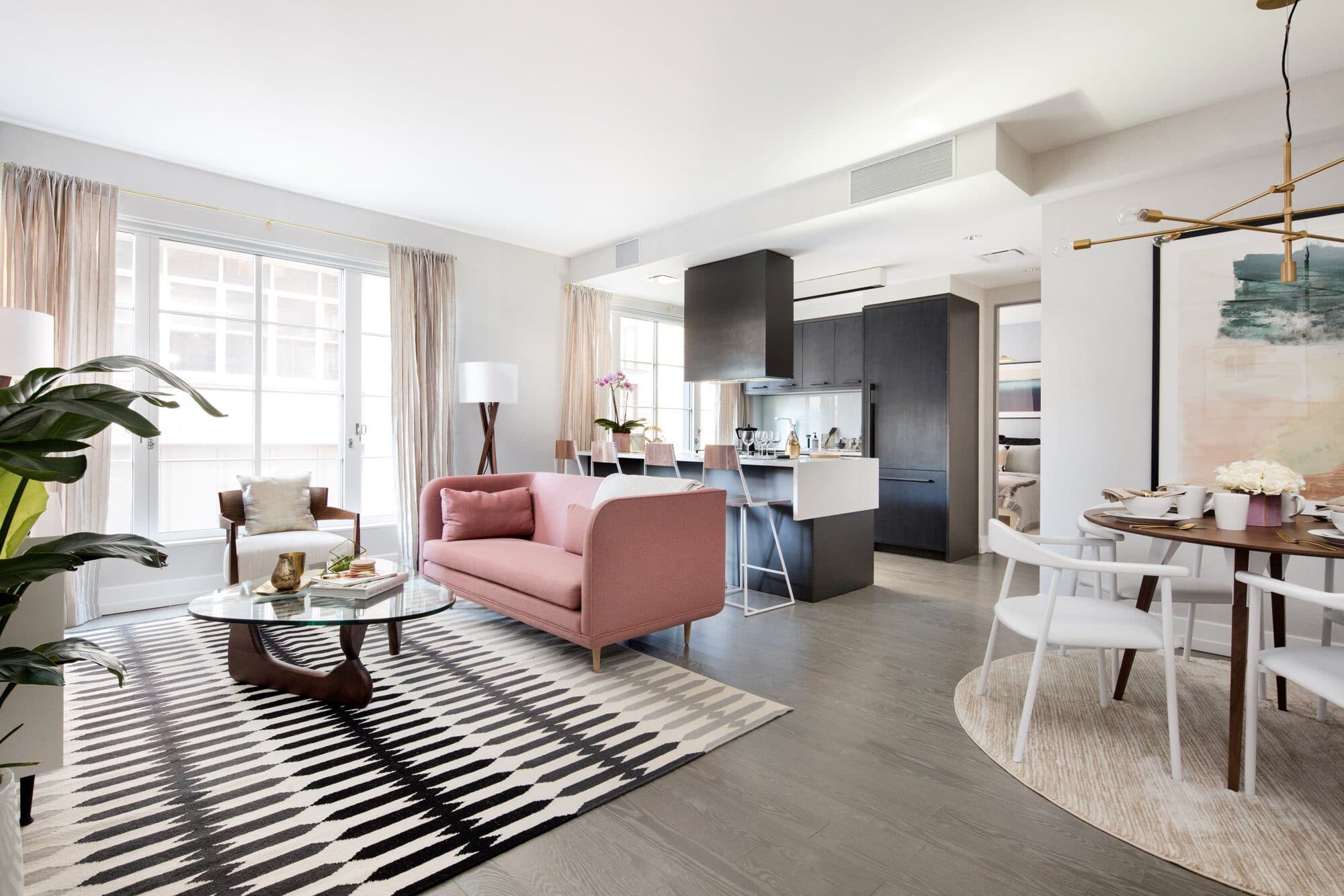 Open living and dining room at 70 Charlton with a blush sofa, a black-and-white striped rug and a dark oak kitchen beyond