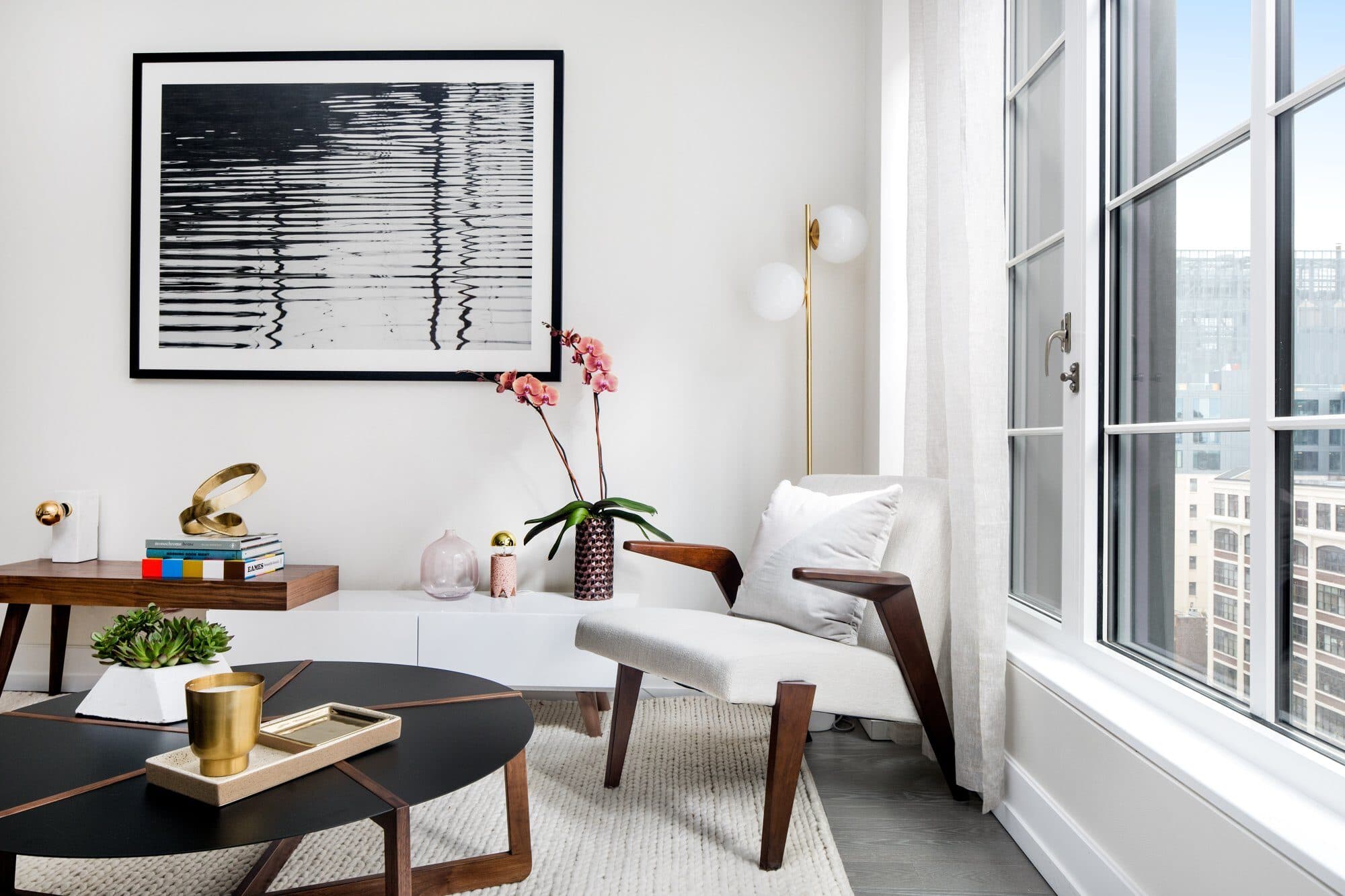 Den with a white lounge chair, an oval black coffee table and a large black-and-white artwork
