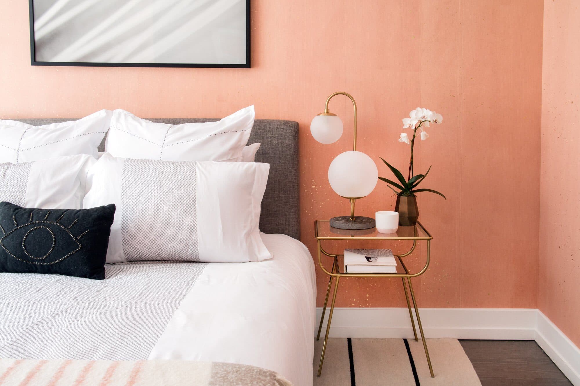 Bed with a brass globe lamp against a coral wall in a 70 Charlton model bedroom