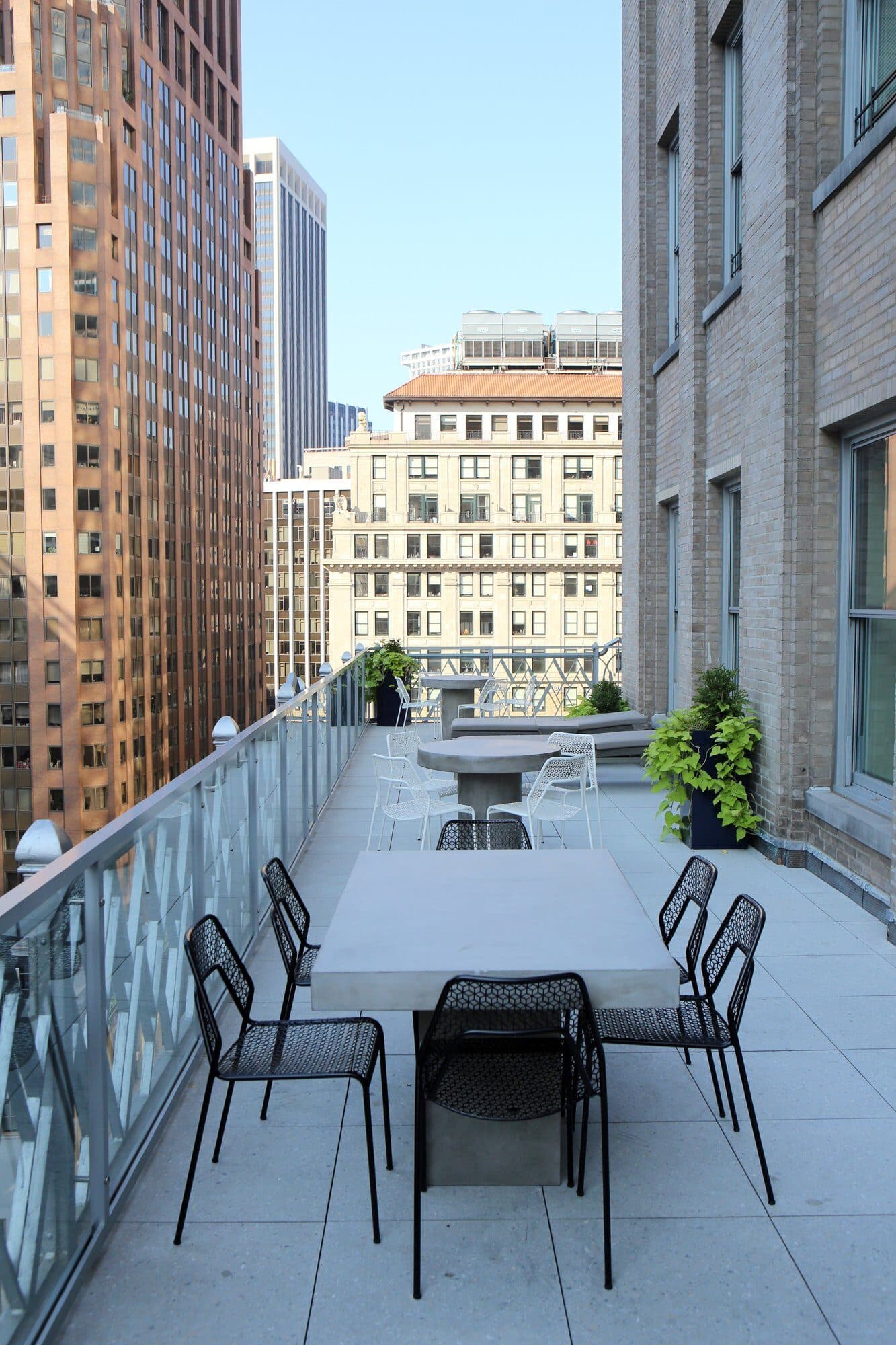 Long terrace dining table with black chairs between towers