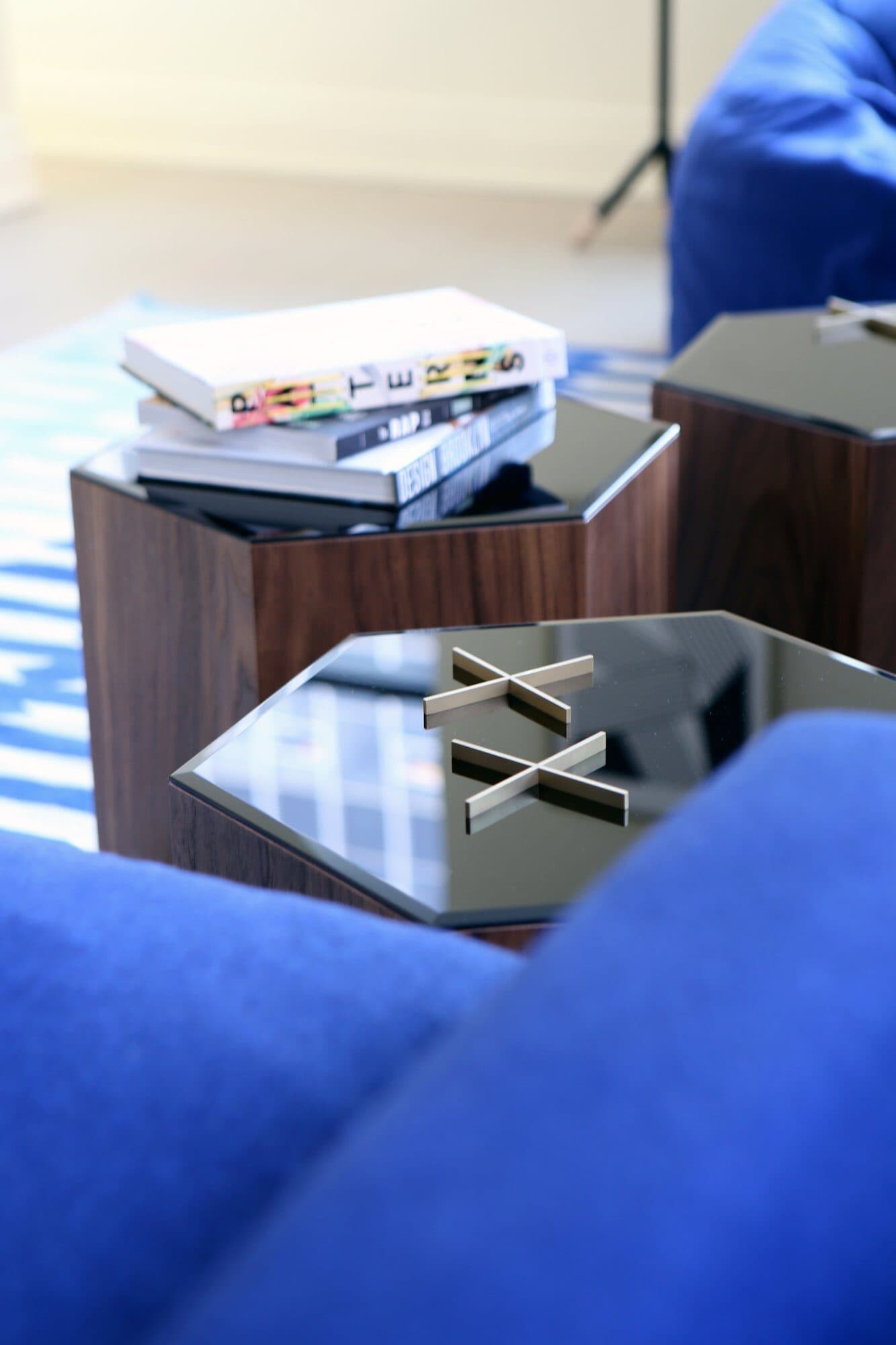 Books on a walnut hexagonal table beside cobalt upholstery