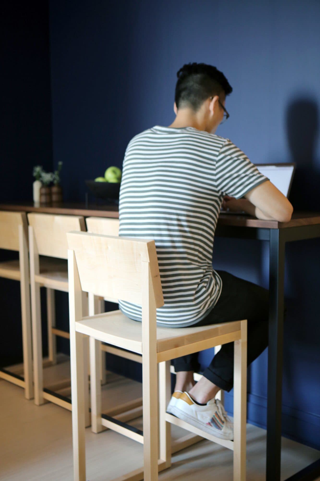 Resident working at the navy counter on a maple stool