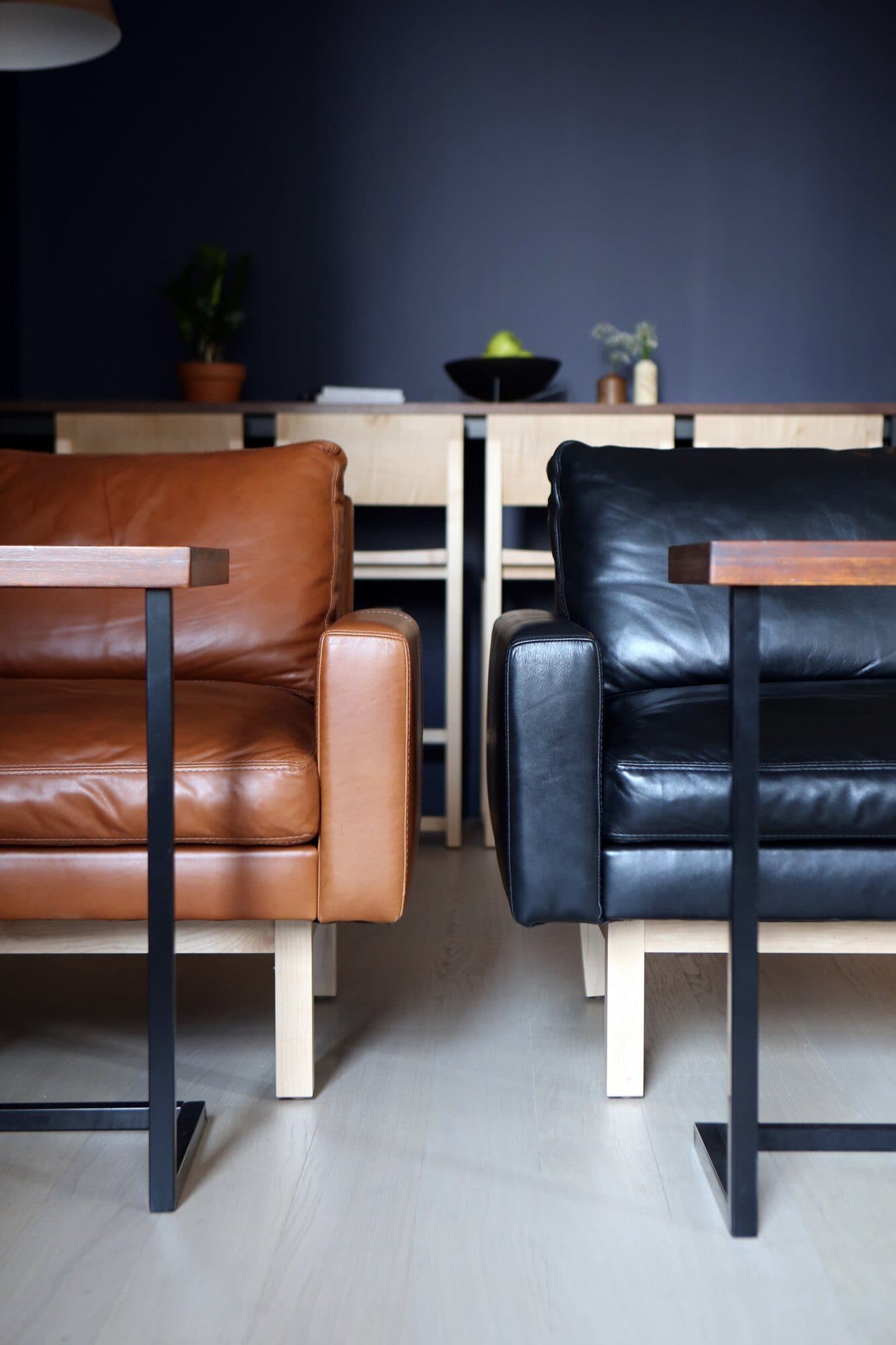 Tan and black leather armchairs on walnut and steel frames