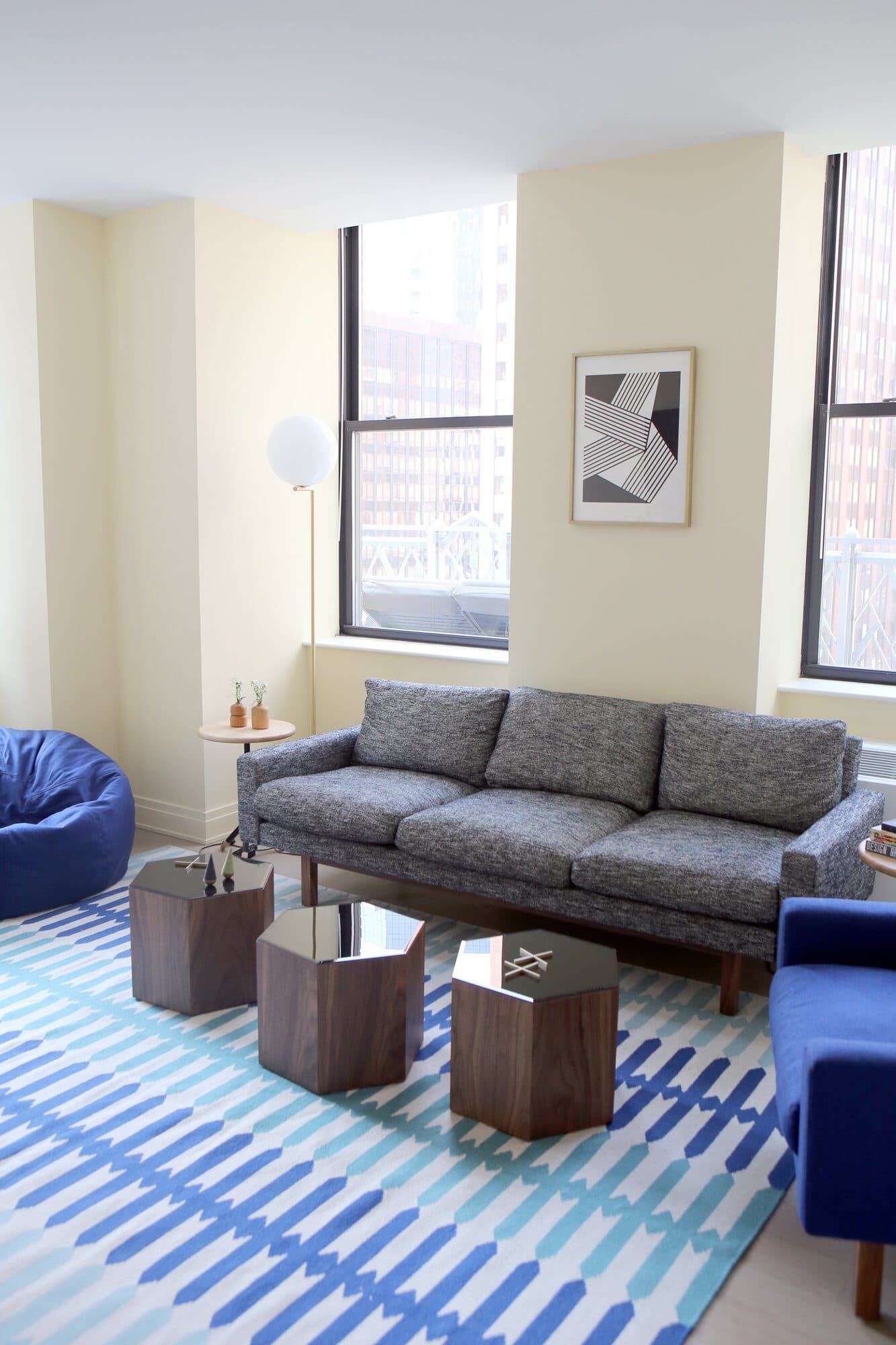 70 Pine resident lounge with a grey sofa, walnut hexagonal tables and a blue patterned rug