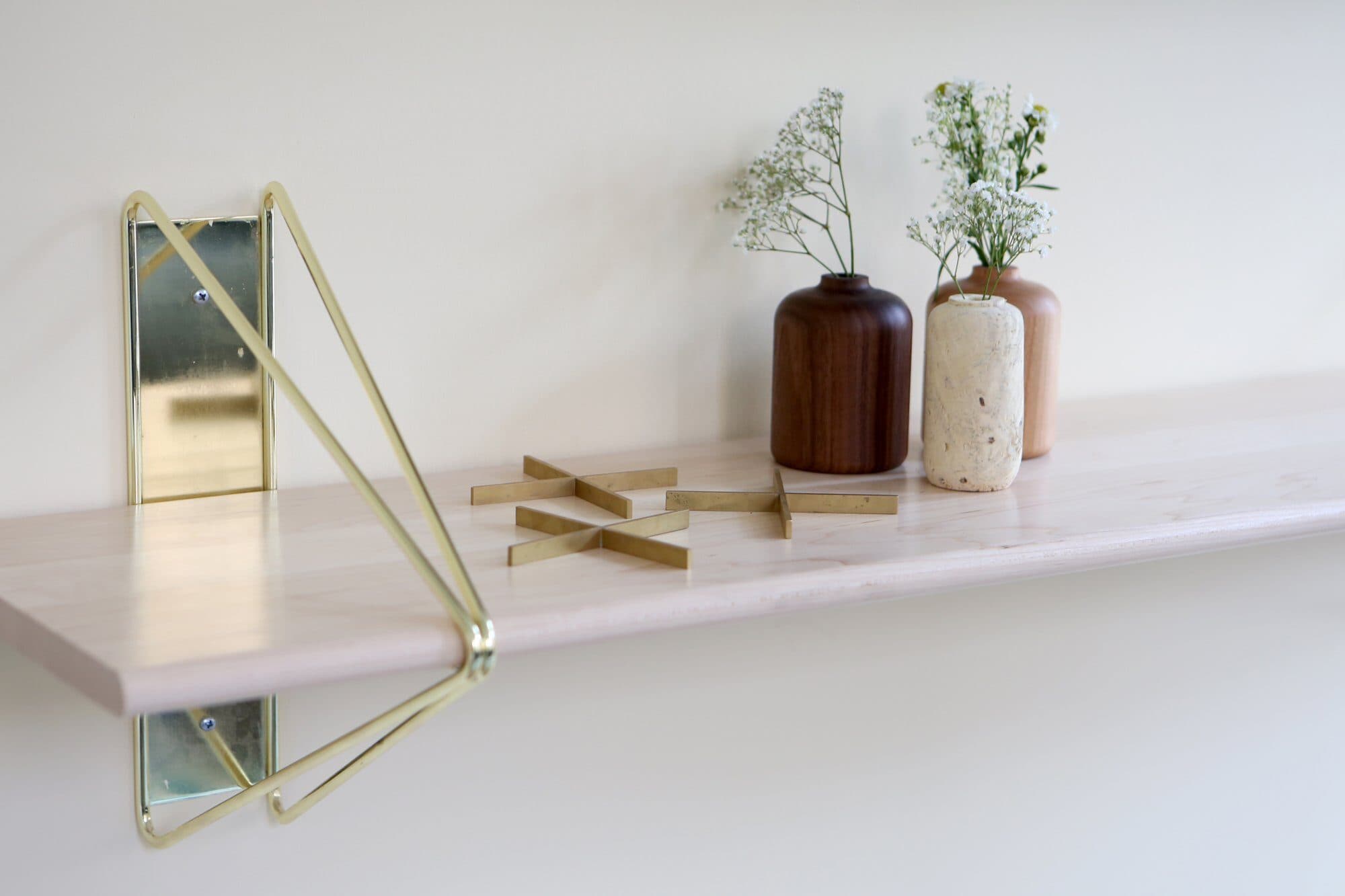 Brass Souda Strut shelf brackets holding vases in the 70 Pine lounge