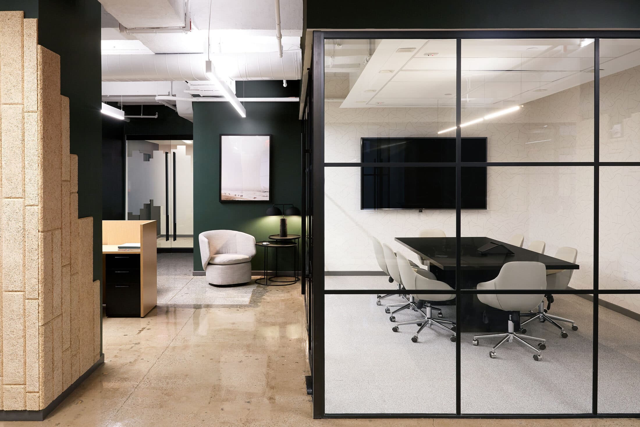 Reception with a sculpted wood wall, a glass-walled conference room, and a cream lounge chair against a green wall