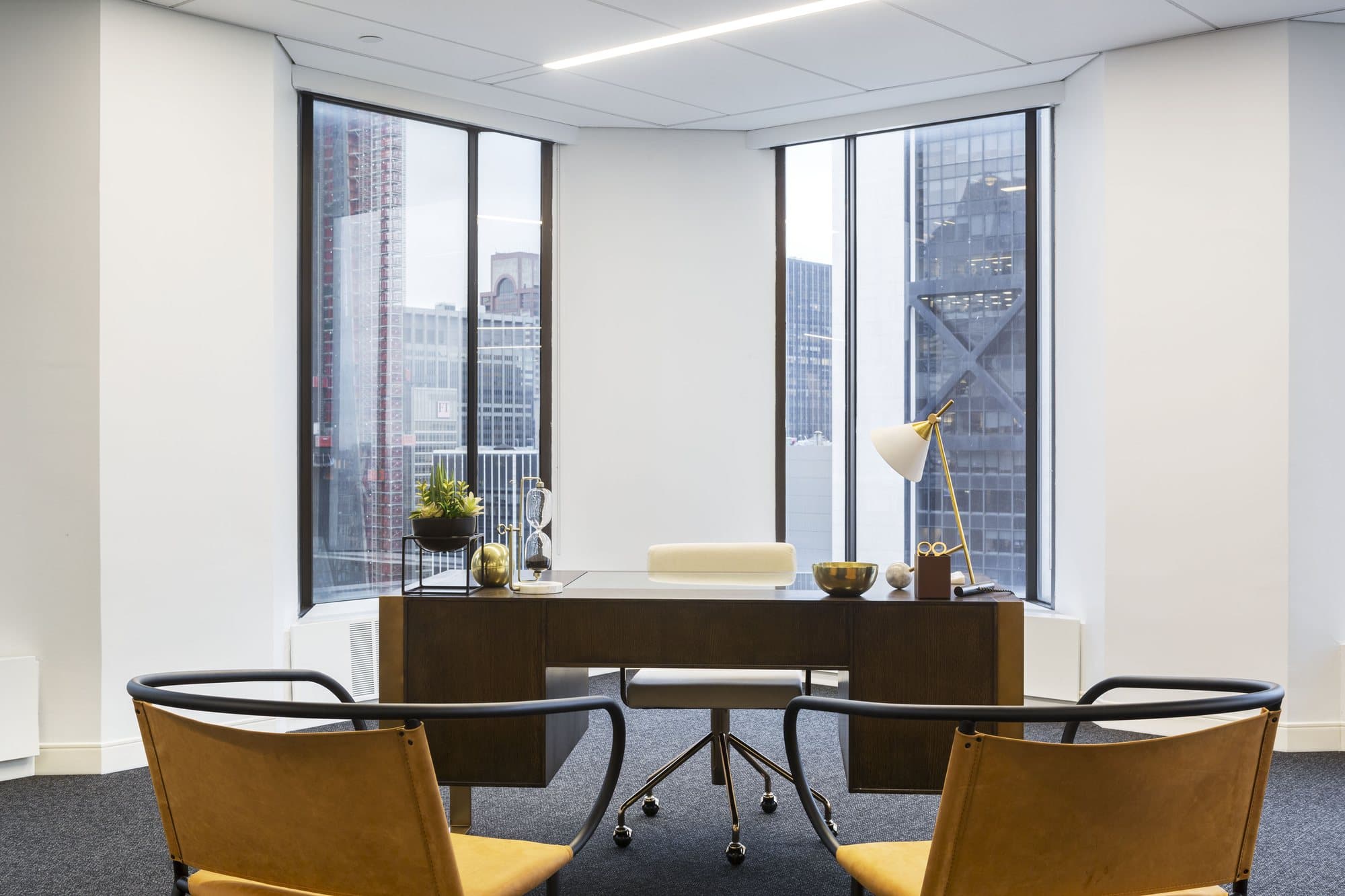 Private office with a walnut desk, mustard-seated armchairs and Midtown towers outside the windows