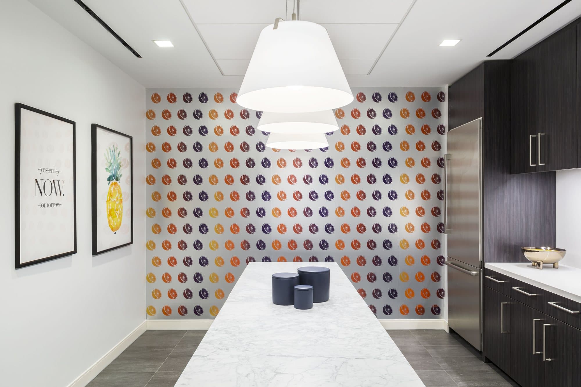 Kitchen in the General Motors Building suite with dotted wallpaper, a marble communal table and white pendant lamps