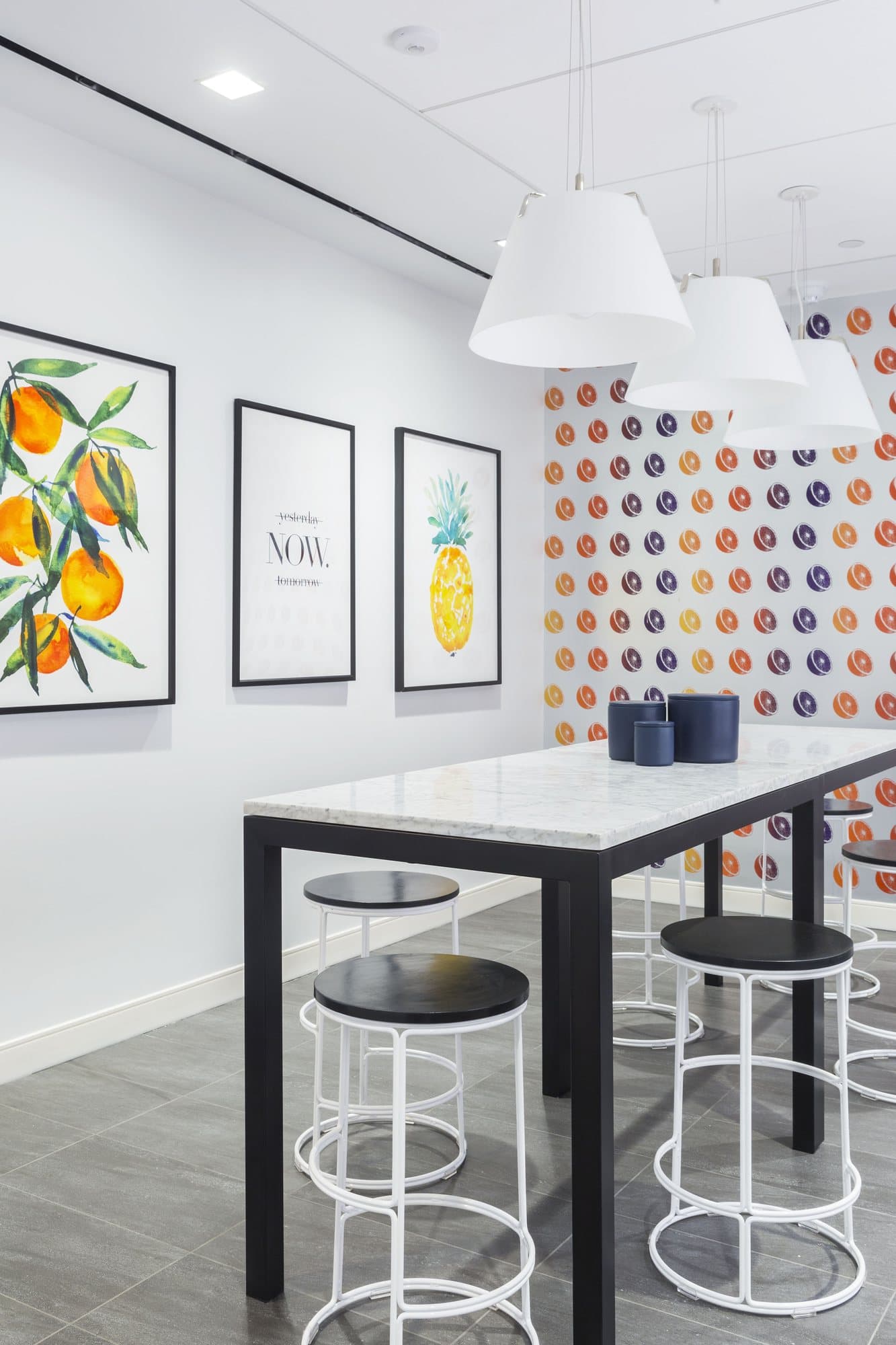 Botanical prints above a marble table with black and white stools