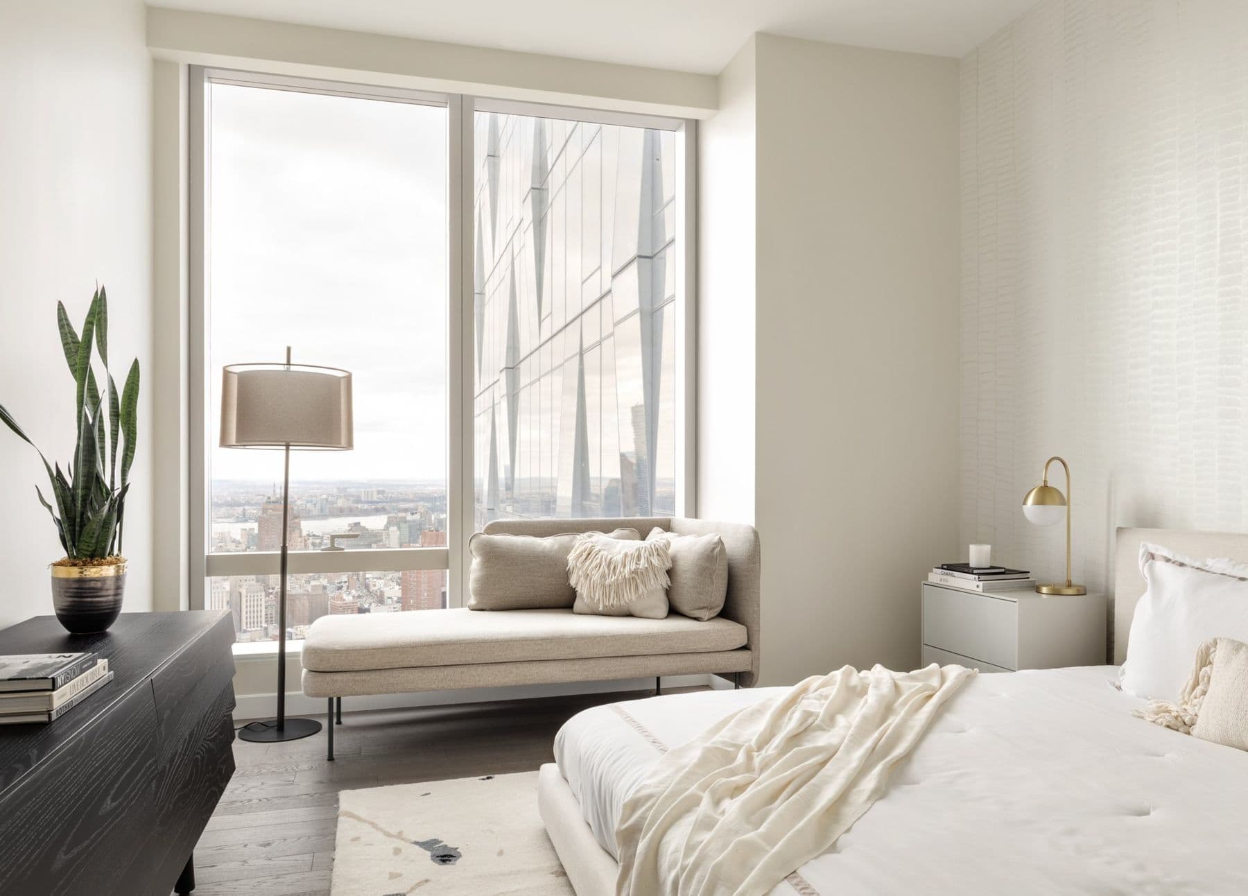 Light bedroom with a chaise by the window and a pale Sarkos wallcovering