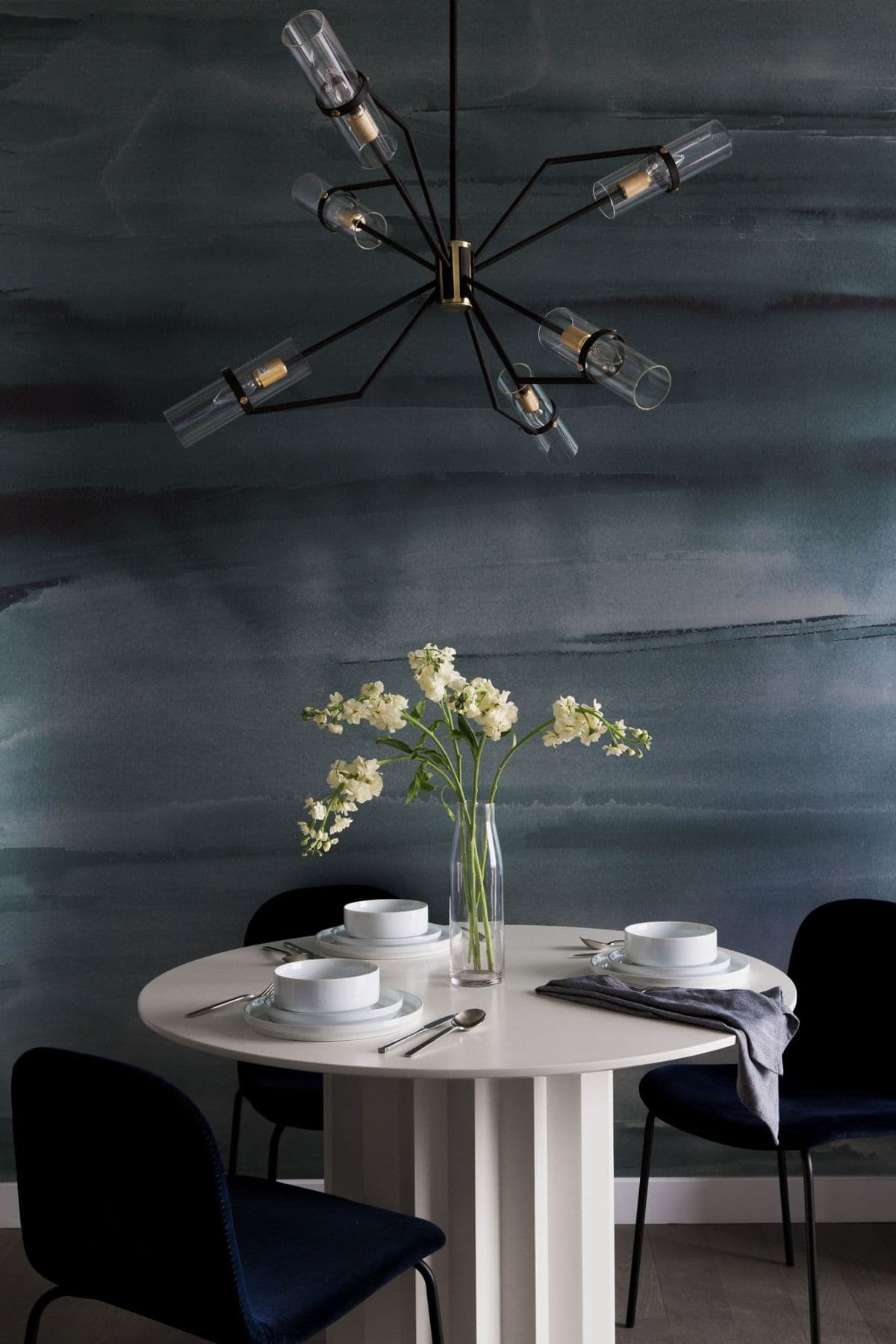 Dining nook under a sputnik chandelier against a smoky watercolor wall