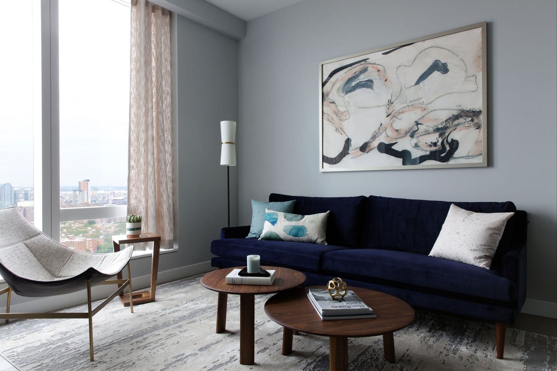 One-bedroom living room with a navy velvet sofa and a sling chair
