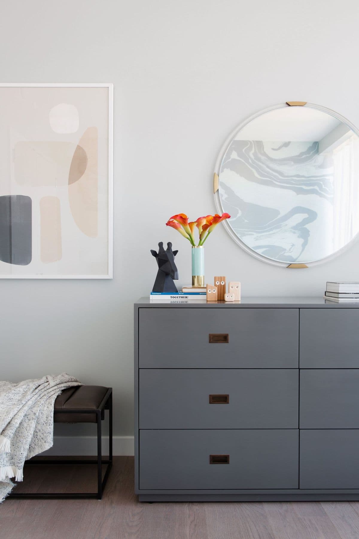 Grey dresser under a marbled mirror and a blush abstract print