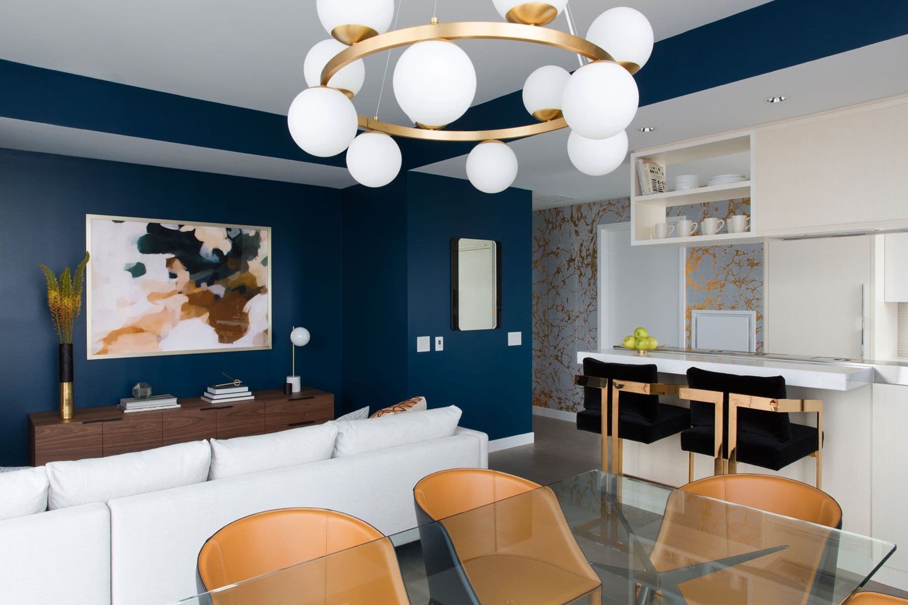 Two-bedroom living and dining room with a brass ring chandelier and caramel leather chairs