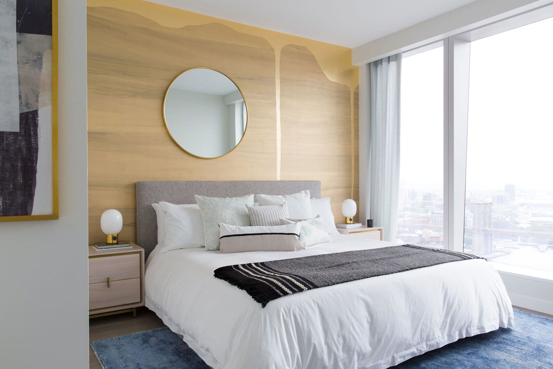 Primary bedroom with a pale wood wall and a round mirror