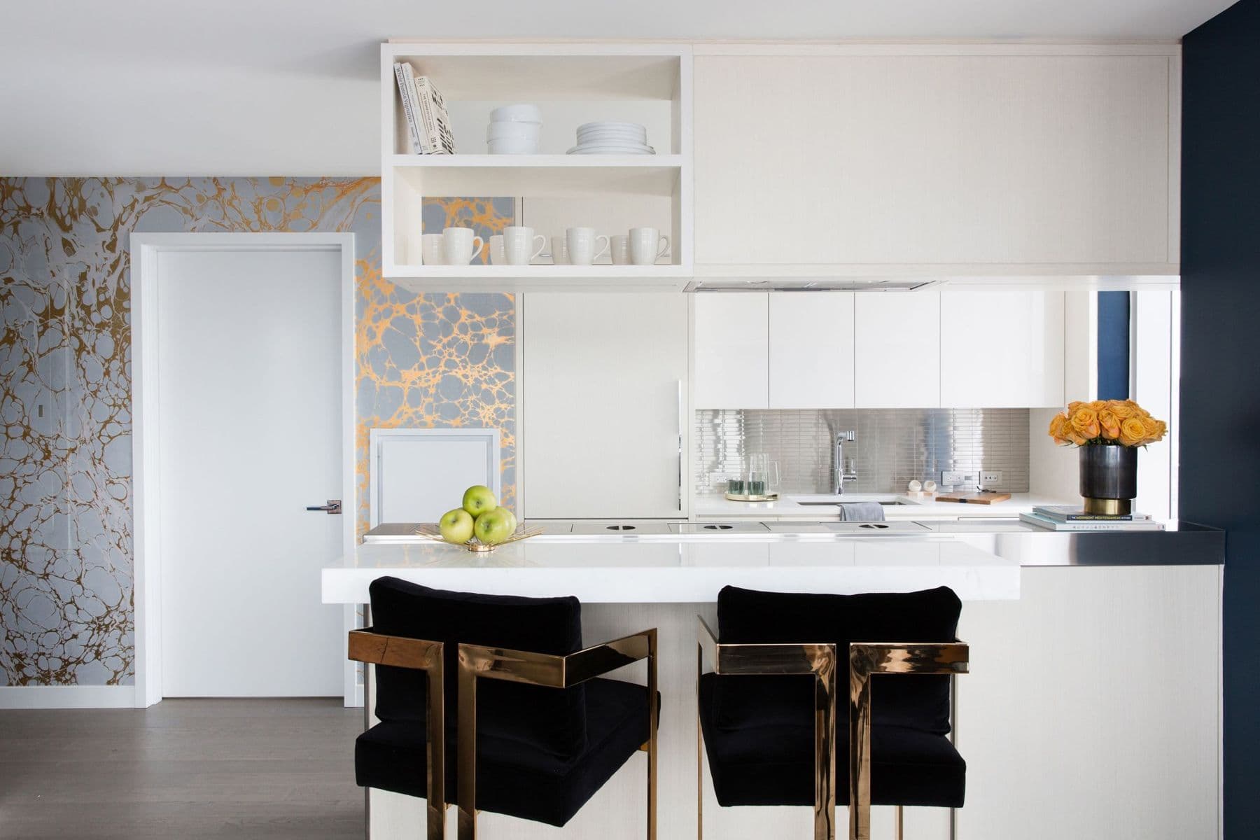 Open kitchen with black velvet counter stools and marbled wallpaper beyond