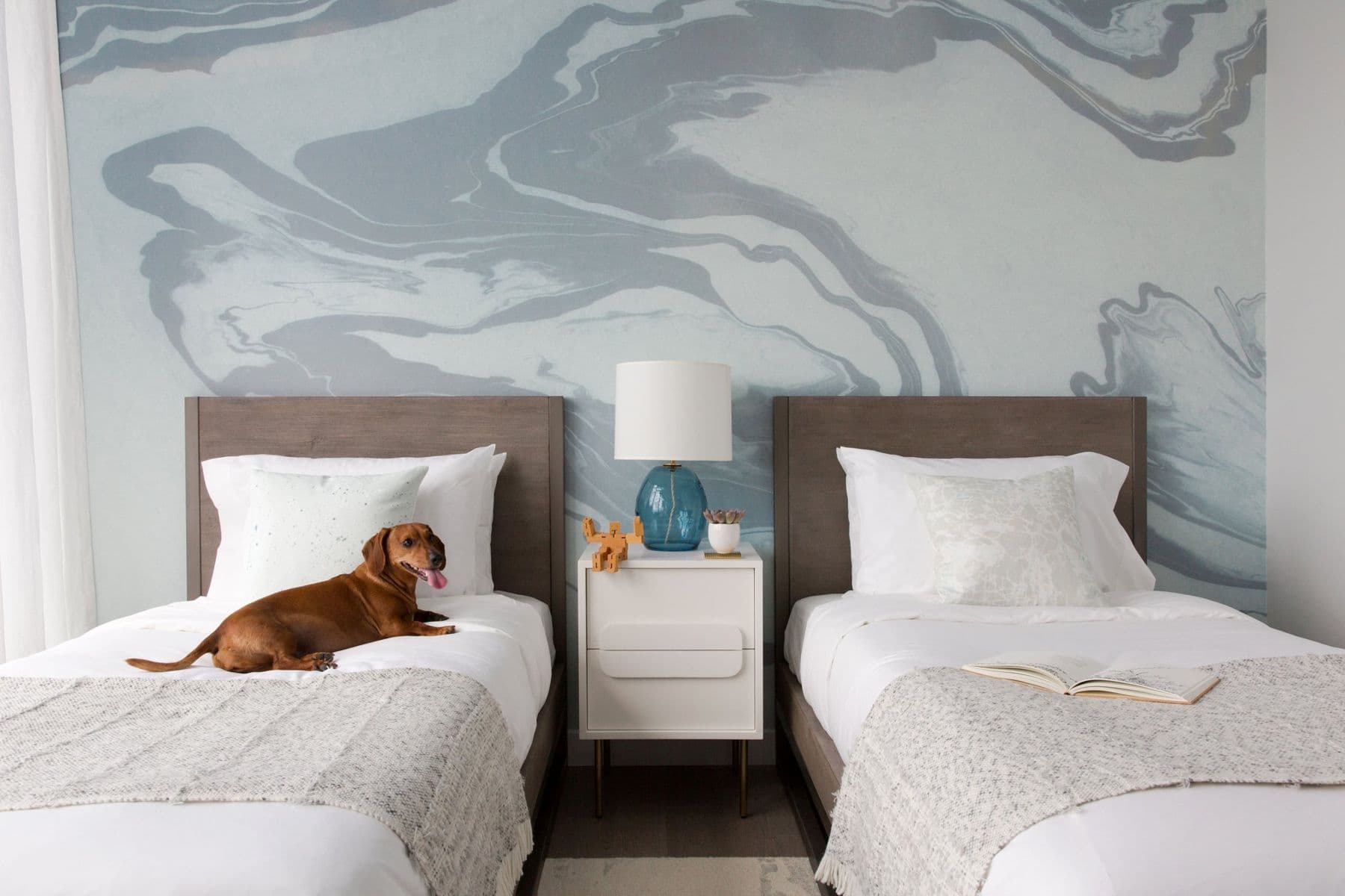 Second bedroom with twin beds under a blue marbled mural